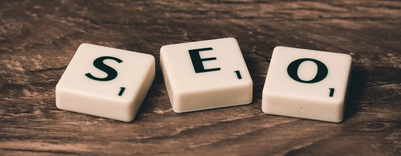 Bir masa üzerinde Scrabble taşlarıyla oluşturulmuş "SEO" yazısı.